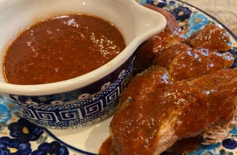 red sauce with specs of pepper and other spices on ribs, chicken and in a blue and white bowl