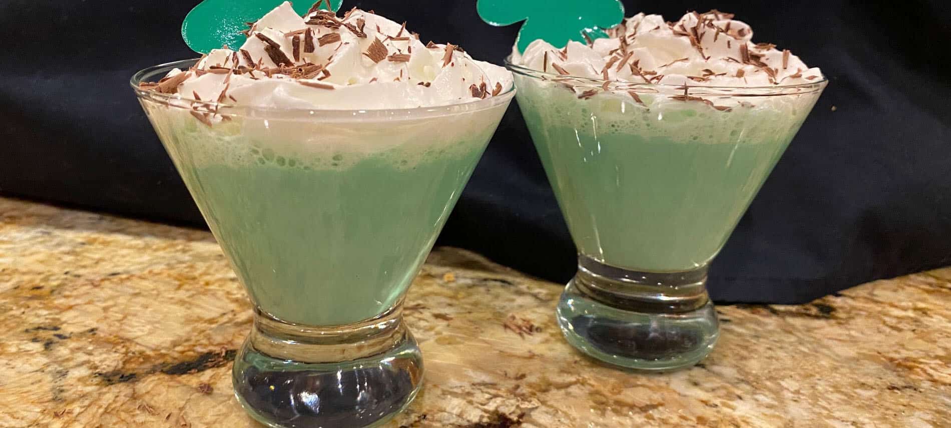 Green Martini with whipped cream topping and chocolate shavings in a clear martini glass