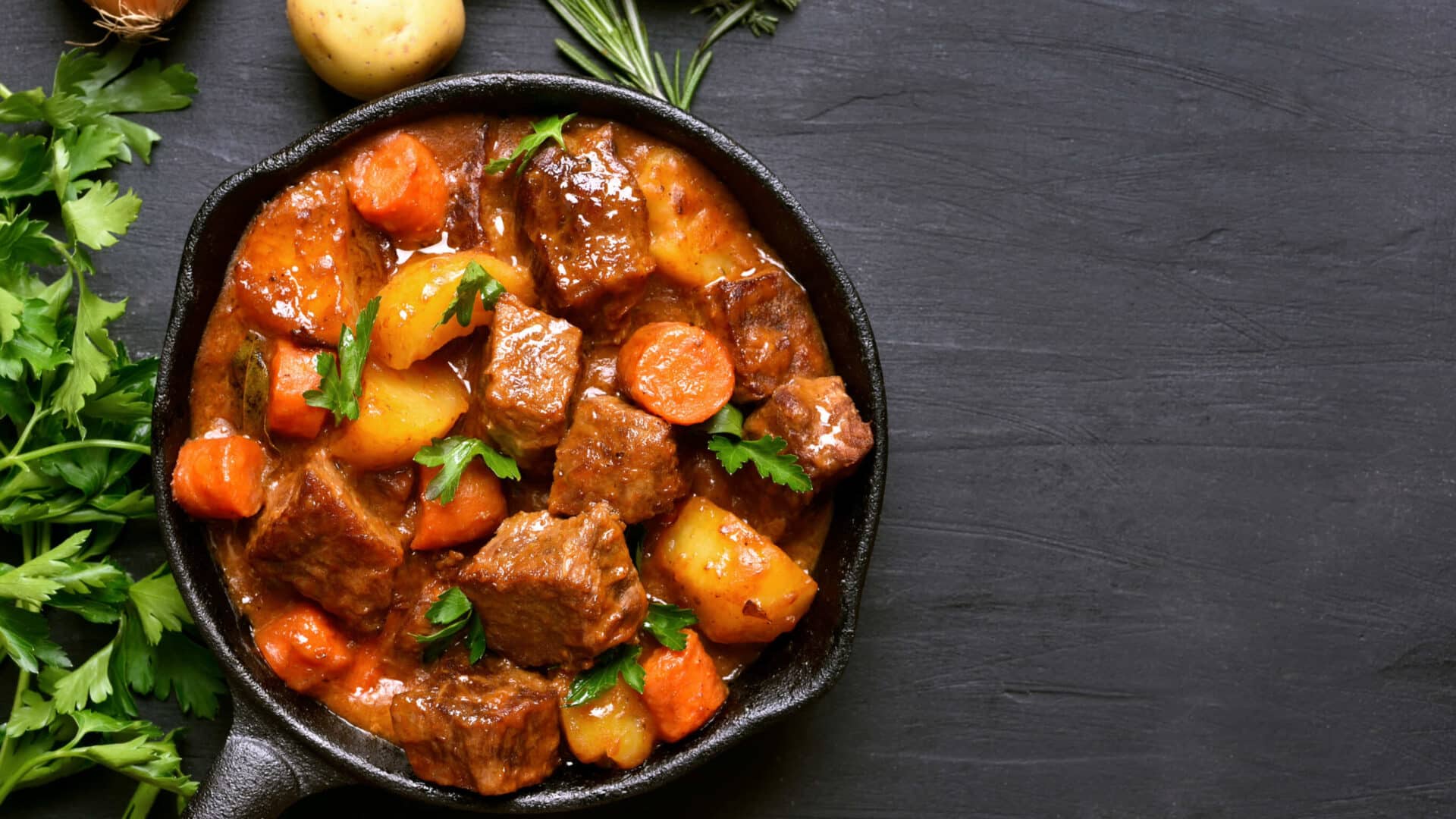 A cast iron pan with beef stew and vetetables