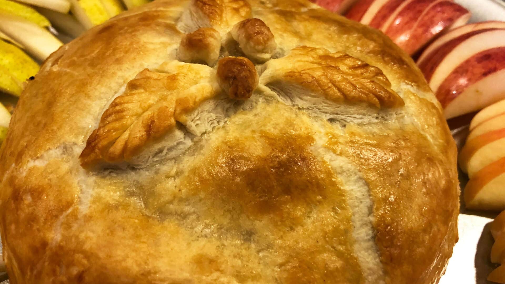 Brie en Croute; golden puff pastry filled with Brie cheese and surrounded by yellpear and red apple slices