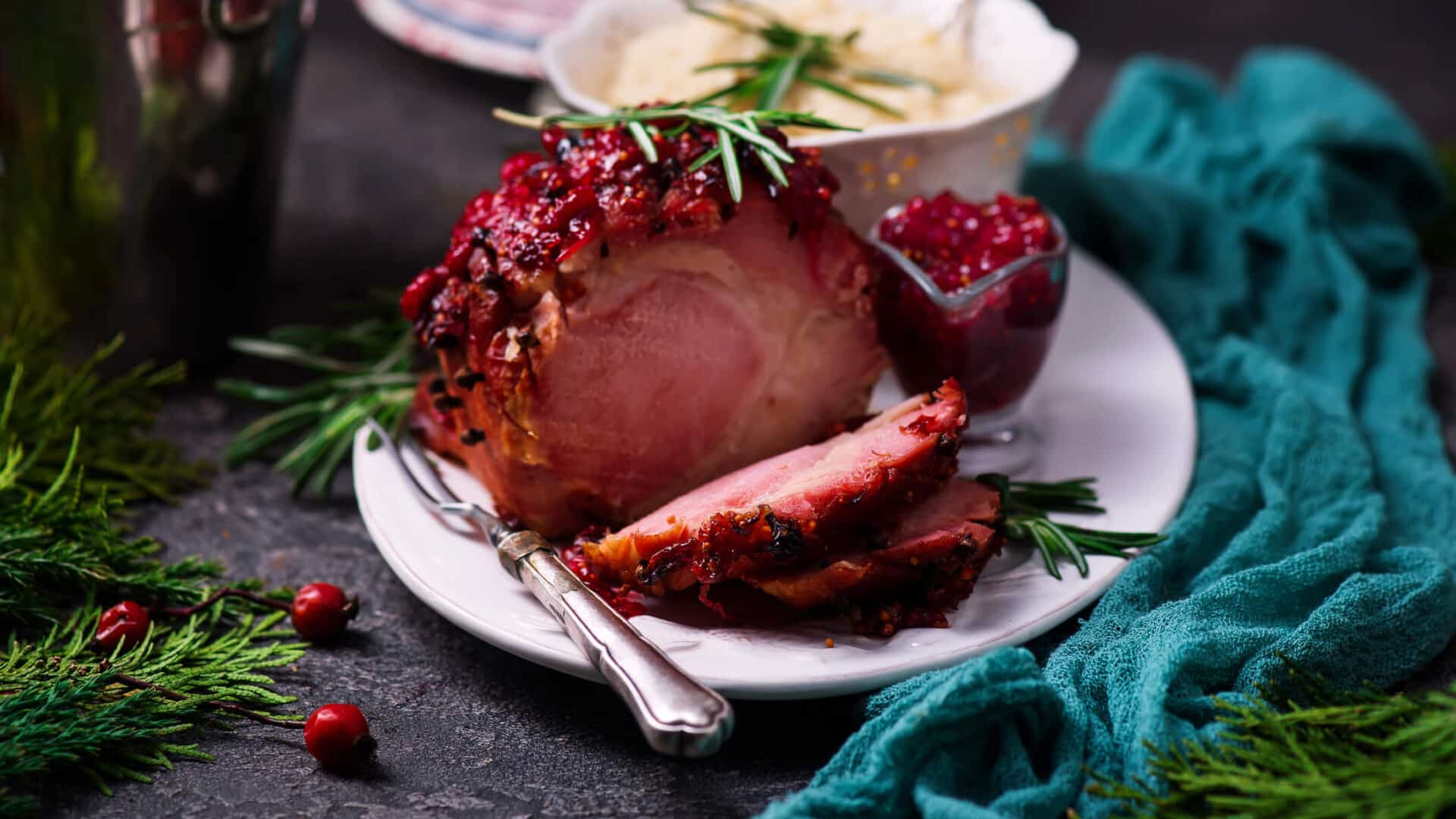 Baked Ham studded with cloves, drizzed with a cranberry glaze, and granished with rosemary