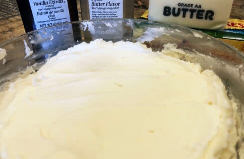 Bowl of white frosting with butter and vanilla extracts, and some butter