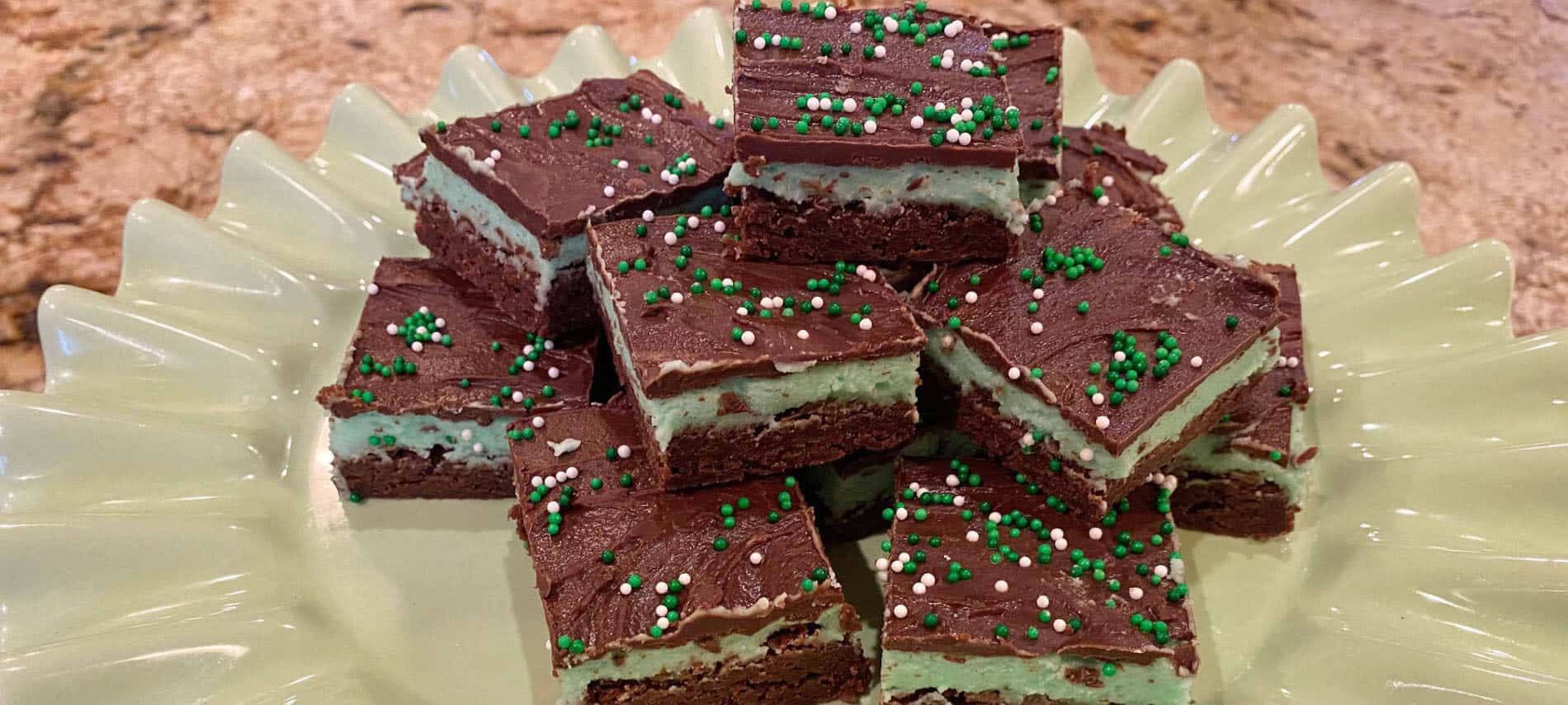 Chocolate brownies with a mint green frosting and chocolate ganache with green and white sprinkles