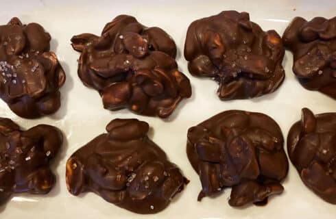 Chocolate covered peanut clusters on a white plate