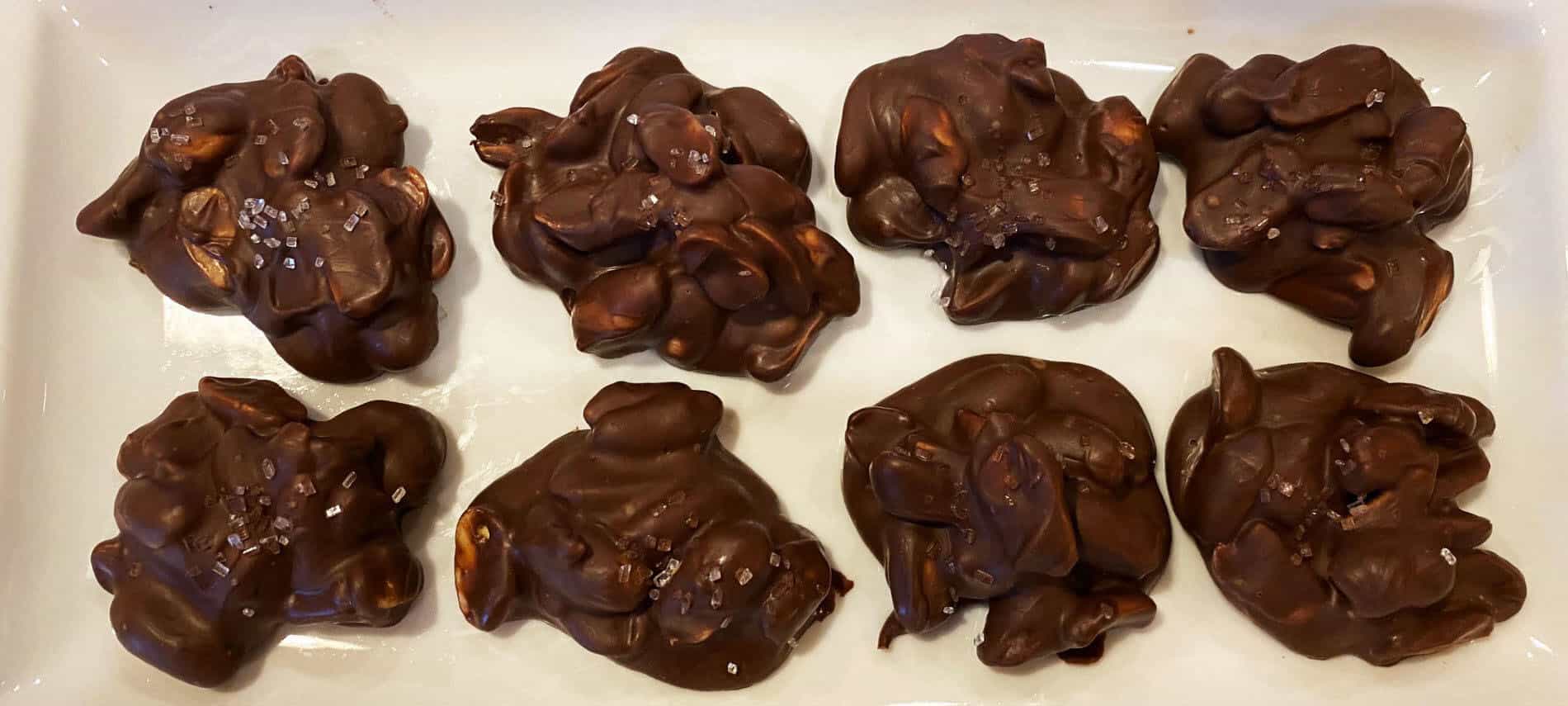 Chocolate covered peanut clusters on a white plate