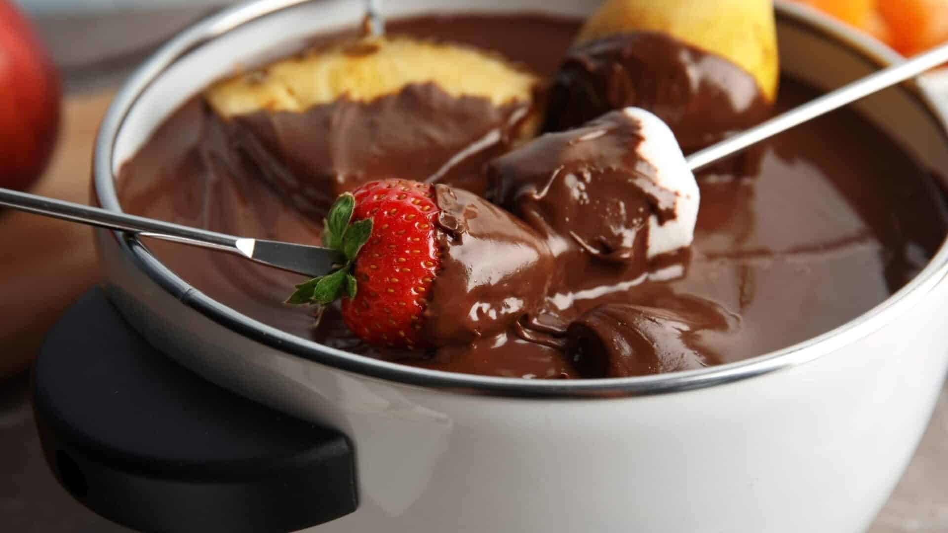Melted dark chocolate with strawberries, bananas and oranges slices dipped in it.