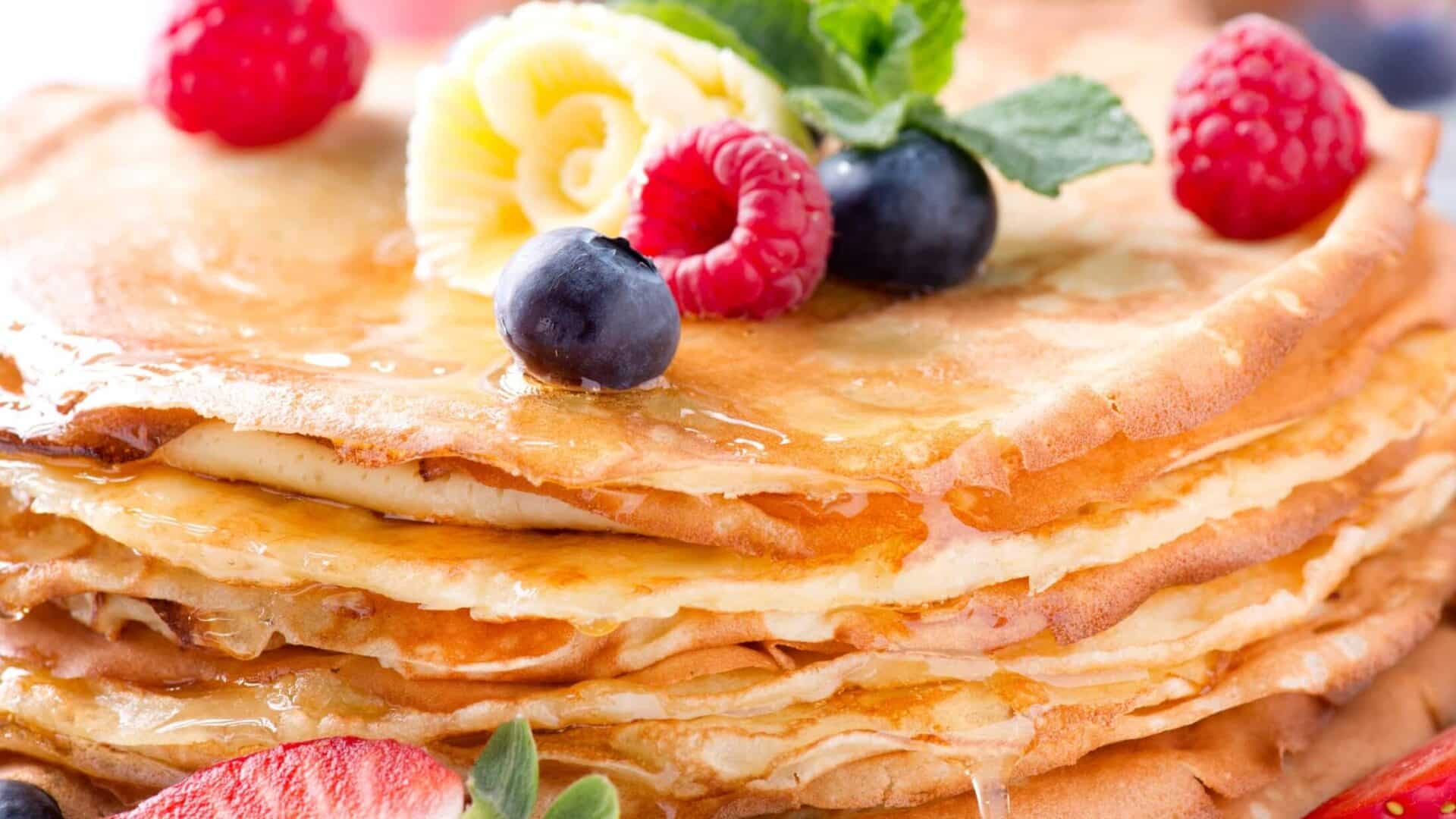 Crepes with berries, a butter flower, and garnished with mint.