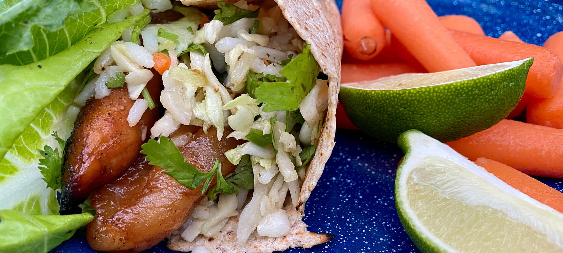 Ginger Chicken Wraps on a blue plate with carrots and limes