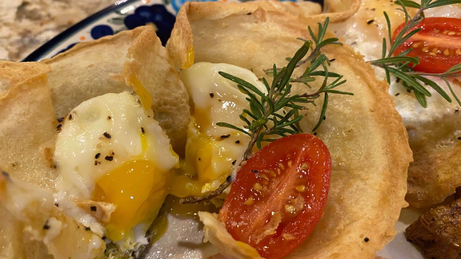 Fluted Crepes filled with a poached egg and runny yolk and cheese with herbs and a sliced tomato