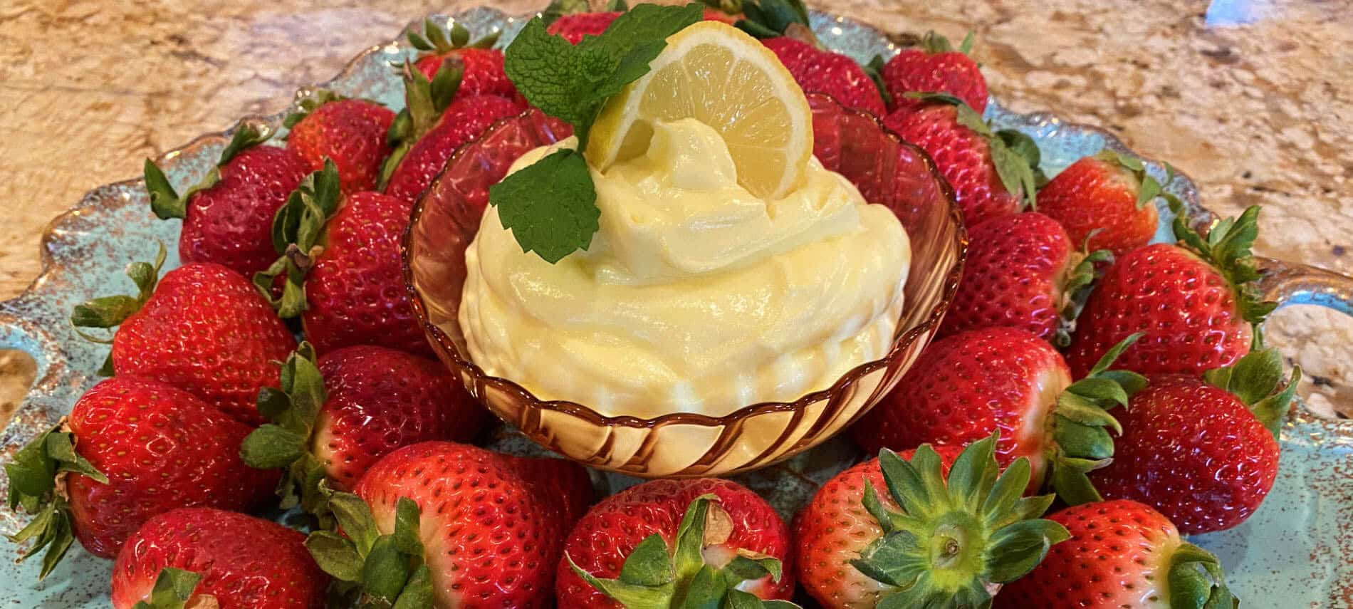 Lemon Dip with a lemon slice surrounded by strawberries