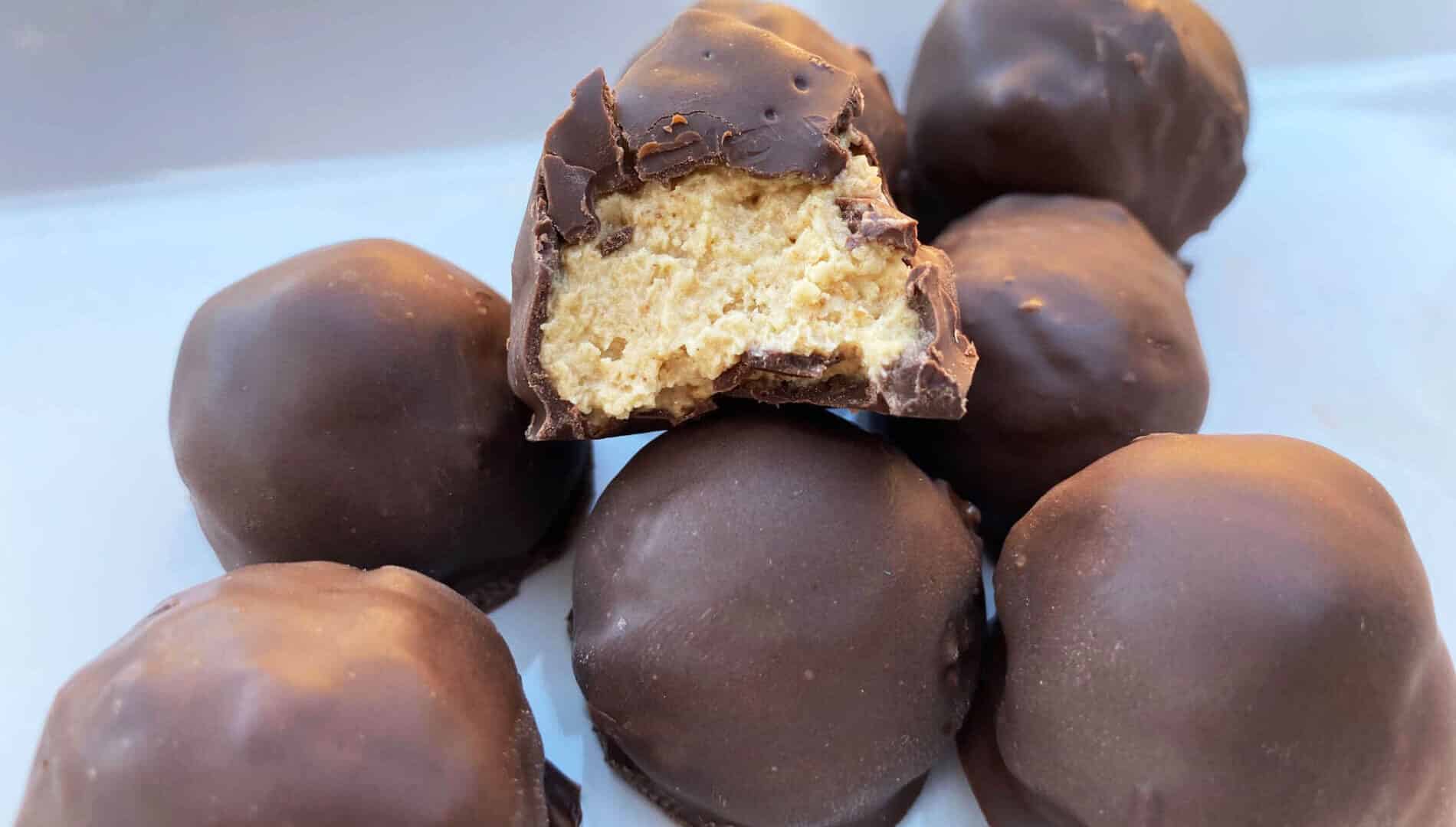 creamy peanut butter balls dipped in dark chocolate on a white plate