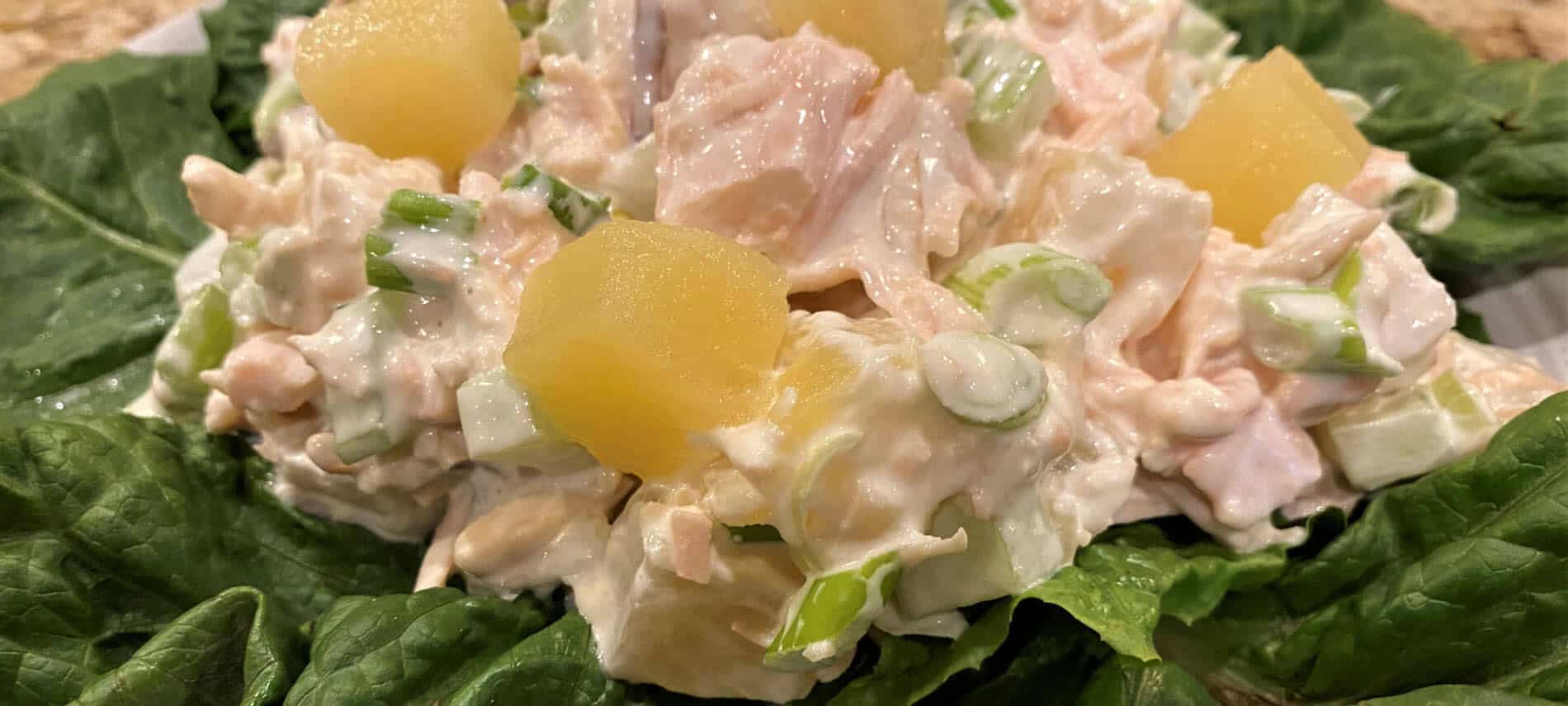 chicken salad with pineapple, green onions, celery, and toasted almonds in a creamy dressing on a bed of green lettuce