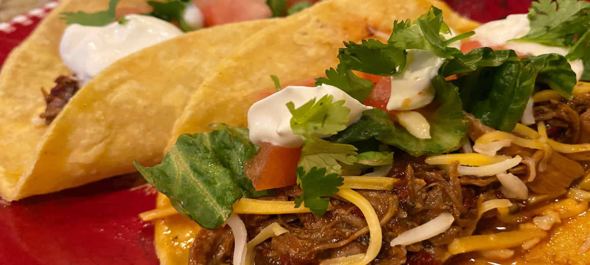 pork tacos with lettuce, tomatoes, shredded cheese and sour cream