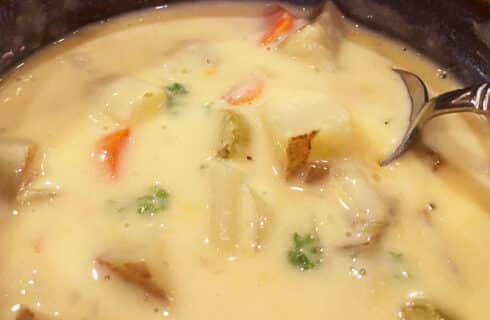 Golden cheesy soup with chunks of potatoes, carrots, onions and celery