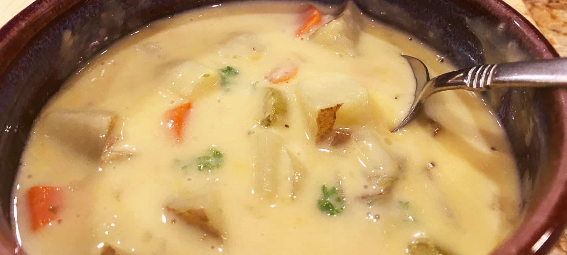 Golden cheesy soup with chunks of potatoes, carrots, onions and celery