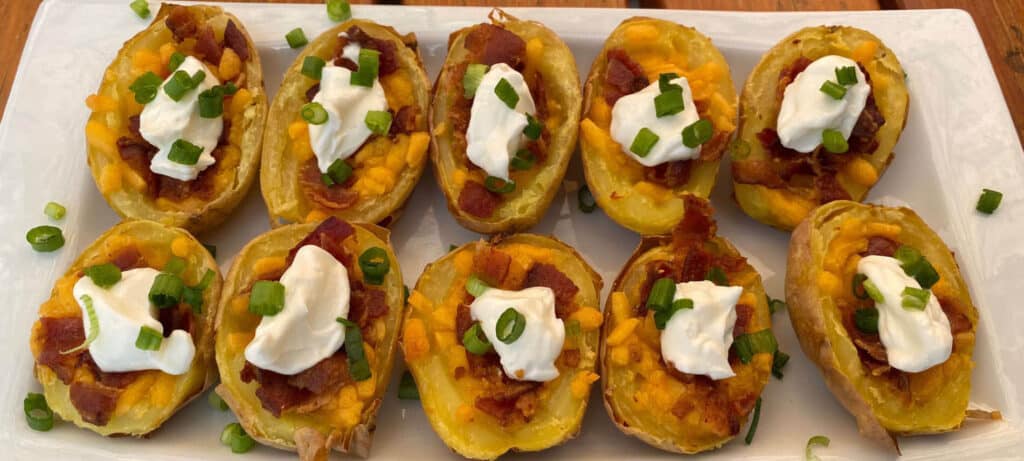 Hollowed out potato skins filled with melted cheddar cheese, crisp bacon pieces, sour cream and chives