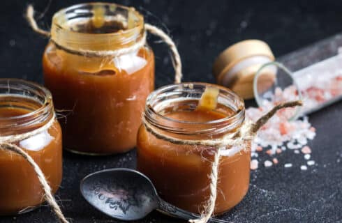 jars of caramel sauce with twine and a spoon, along with chunky sea salt