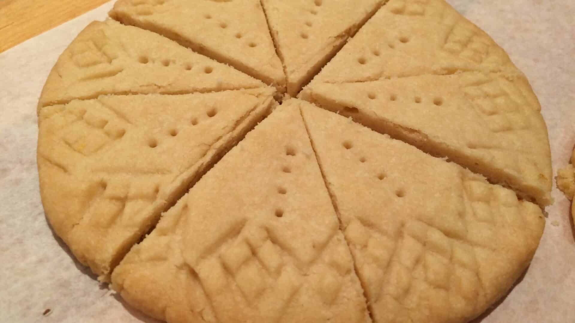 Round golden disc of buttery cookies cut into wedges with criss-cross edges