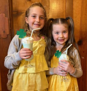 2 girls in yellow dresses with a green milkshake