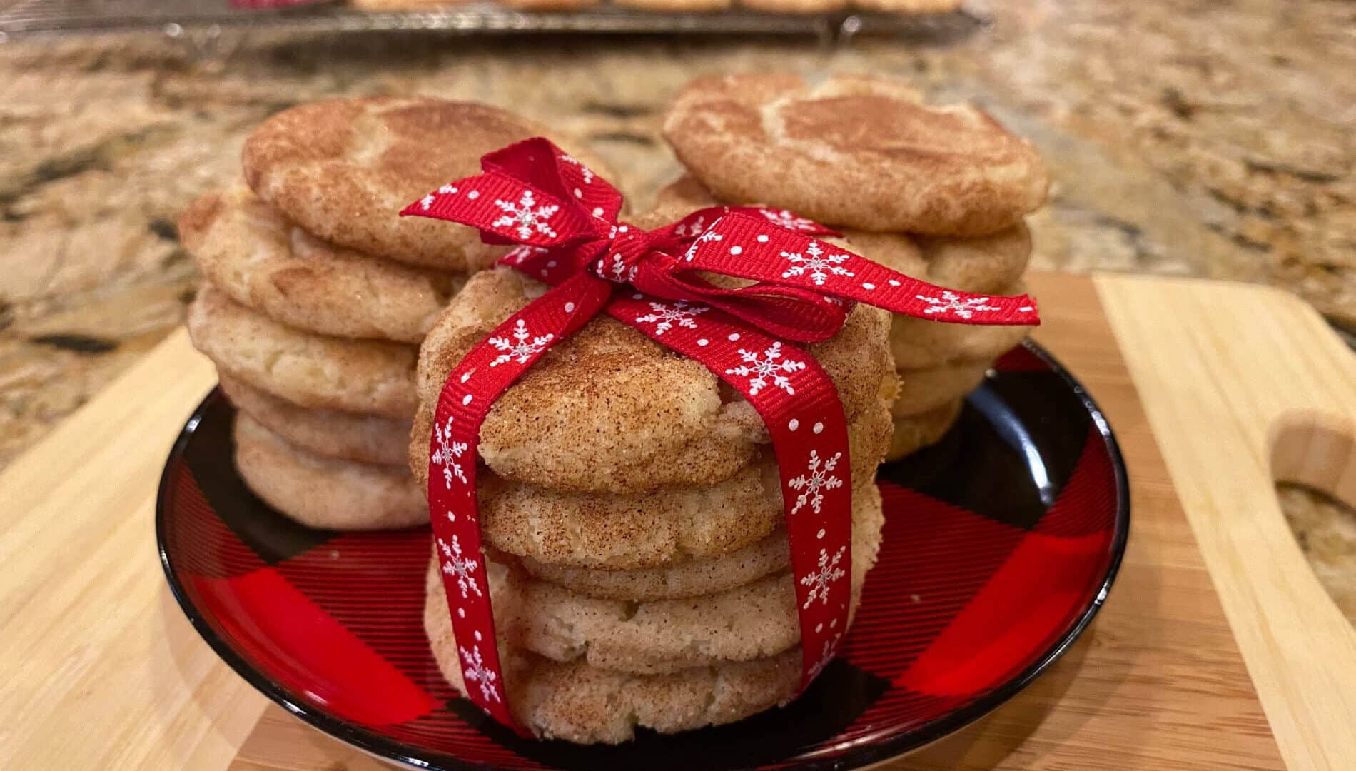 Golden round cookies coated with cinnamon and sugar, stacked and wrapped witjh a red and white snowflake ribbon