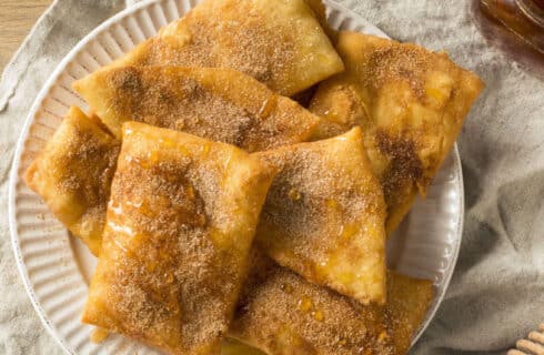 rectangular fried sopapillas sprinkled with cinammon and sugar and drizzled with honey