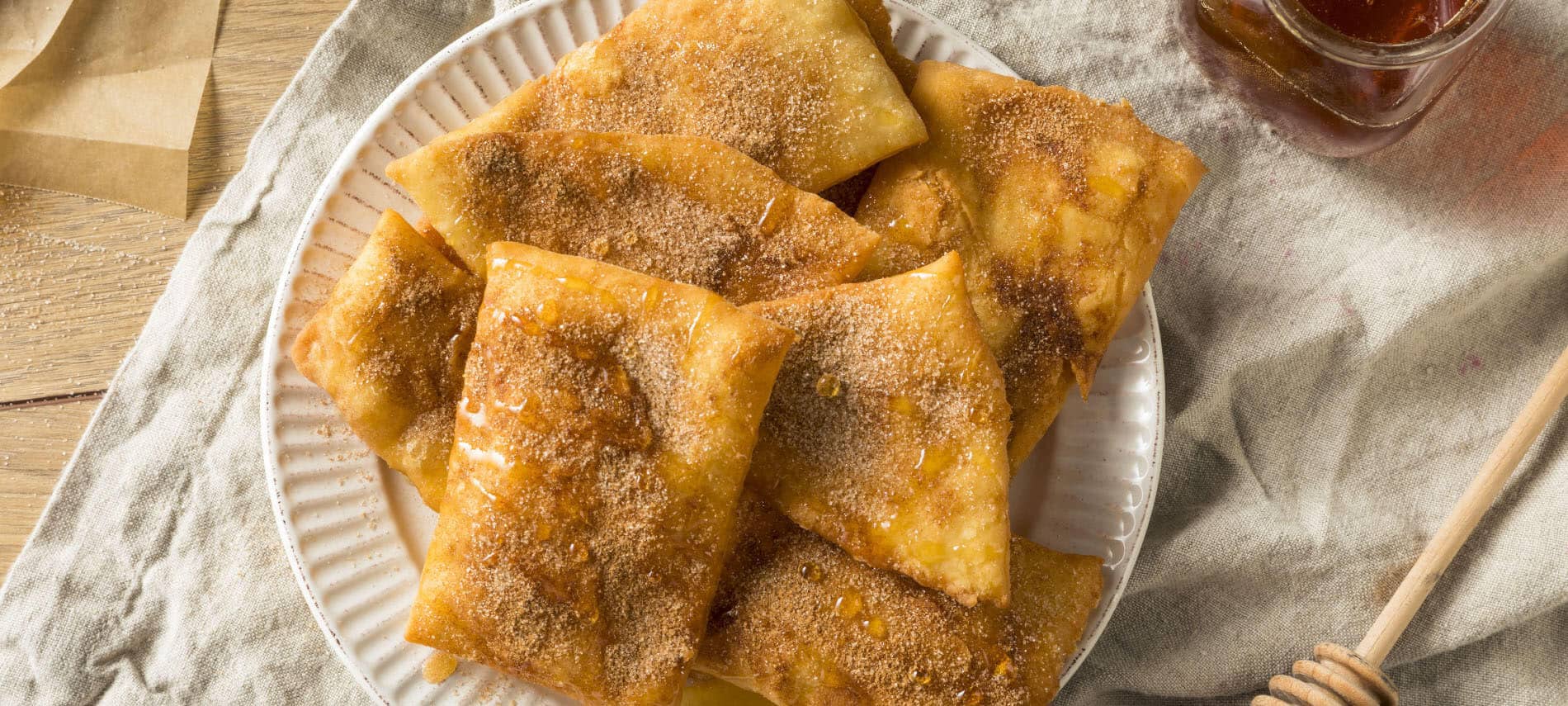 rectangular fried sopapillas sprinkled with cinammon and sugar and drizzled with honey