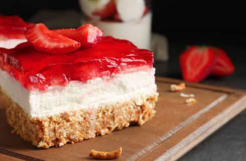layered strawberry dessert with a pretzel crumb crust, cream filling, and red strawberry jello toppiing