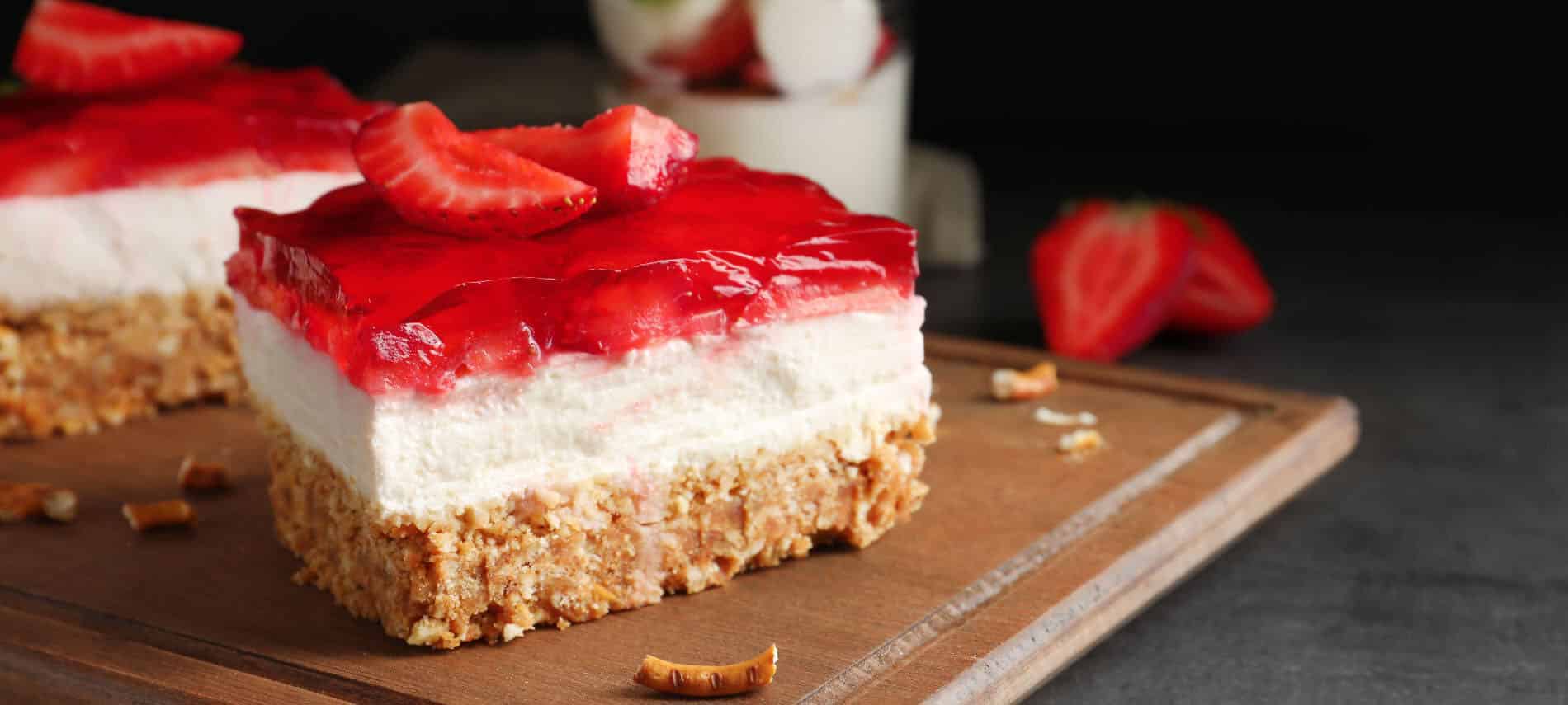 layered strawberry dessert with a pretzel crumb crust, cream filling, and red strawberry jello toppiing