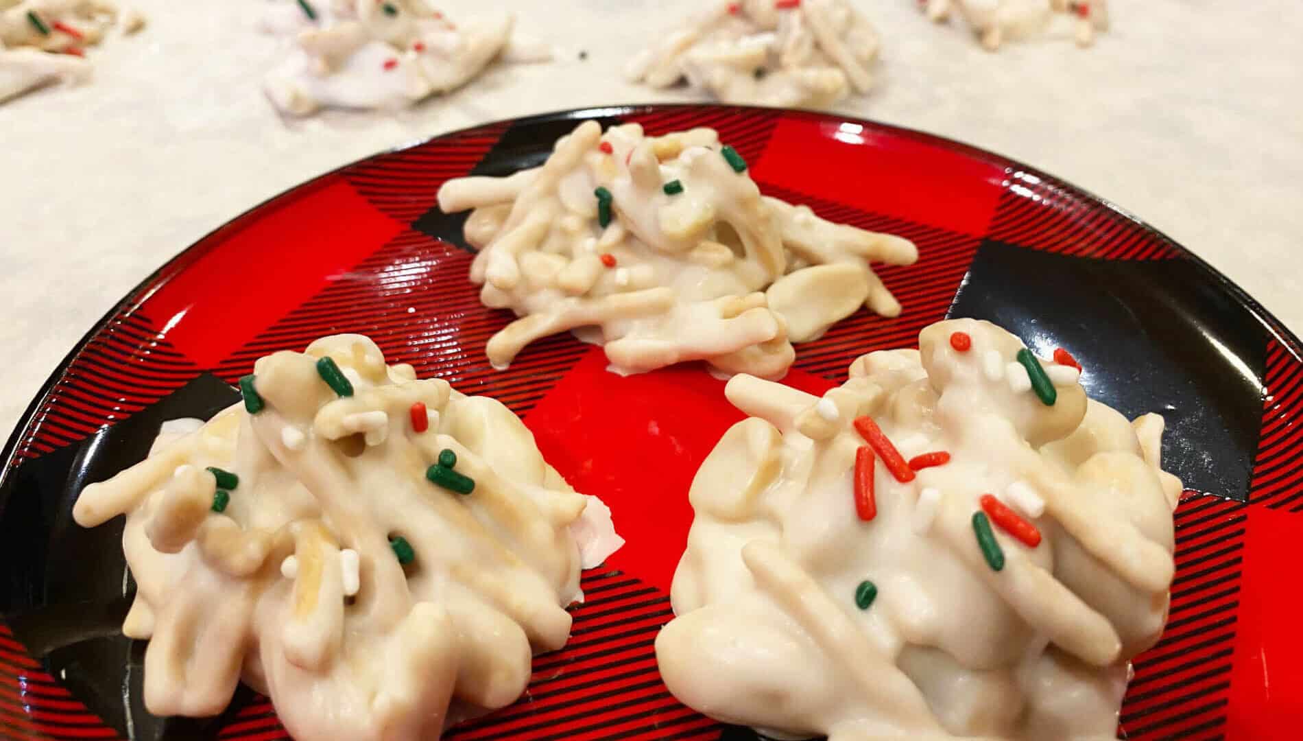 white candy with crispy chow mein noodles, salted peanuts and green, white and red sprinkles on a red and black checkered plate