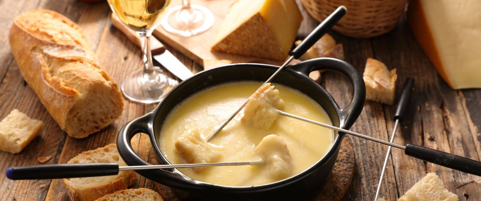 cheese fondue with bread and a wedge of cheese on the side