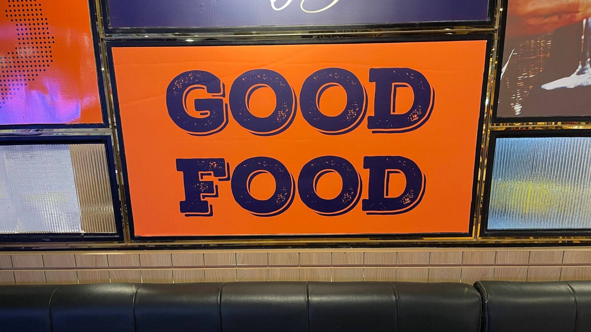 an orange sign with blue writing that says GOOD FOOD