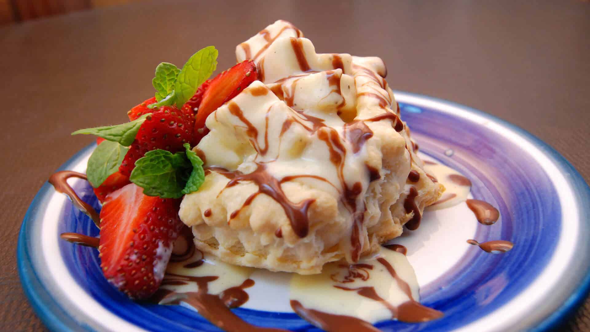 creamy chopped bananas in a puff pastry shell drizzled with chocolate and garnished with fresh strawberries