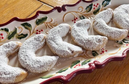A rectangular Christmas tray with crescent shaped peanut butter cookies dusted with powdered sugar.