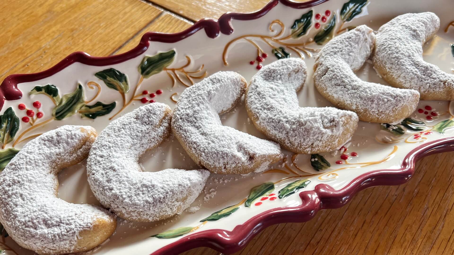 A rectangular Christmas tray with crescent shaped peanut butter cookies dusted with powdered sugar.
