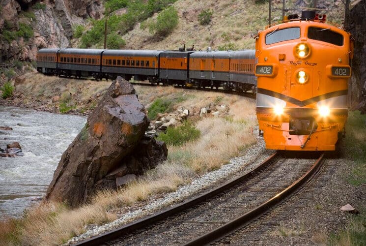 an orange train winding along a river