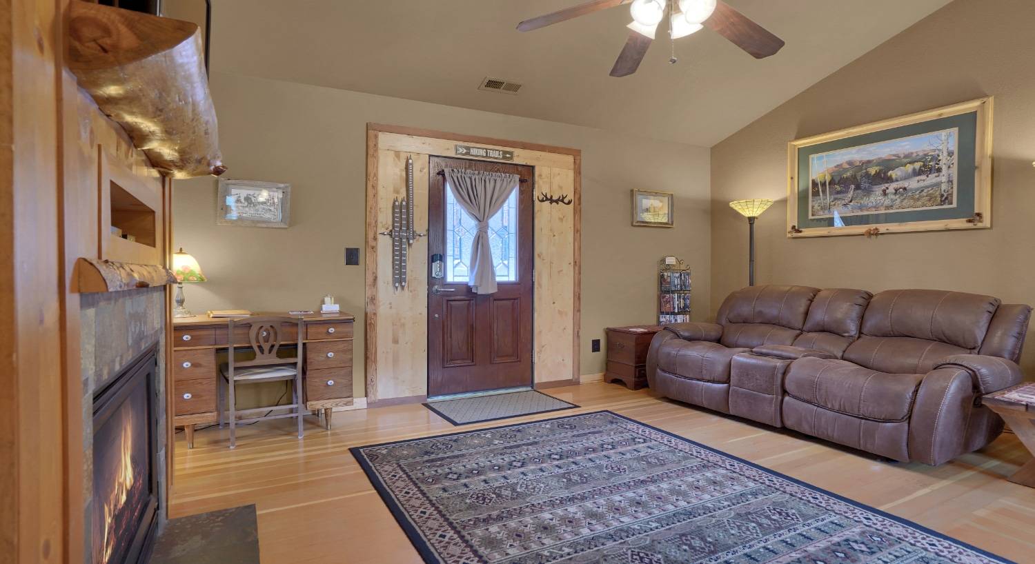 sitting room with sofa, front door, writing desk, ceiling fan, and large area rug