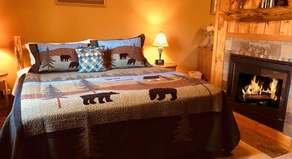 Rustic king bed with bedside tables in front of the fireplace