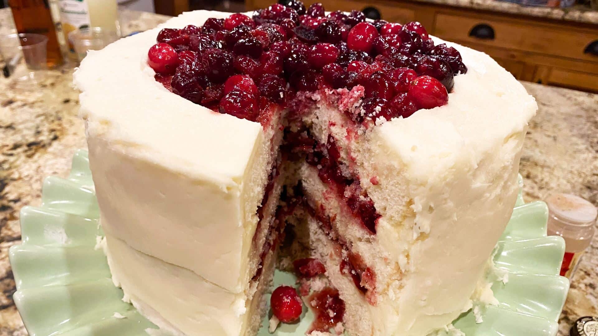 layered white cake with a cranberry filling, frosted with a white frosting and topped with more cranberry topping.