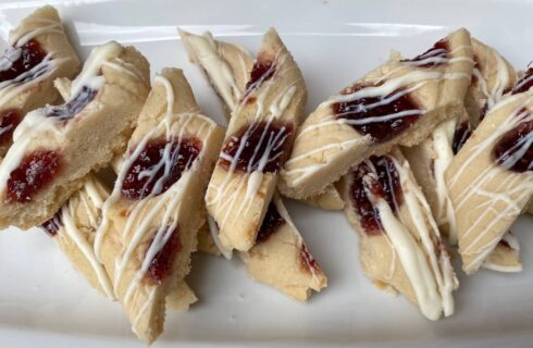slices of shortbread cookies with ribbons of raspberry jam and drizzled with a white icing.