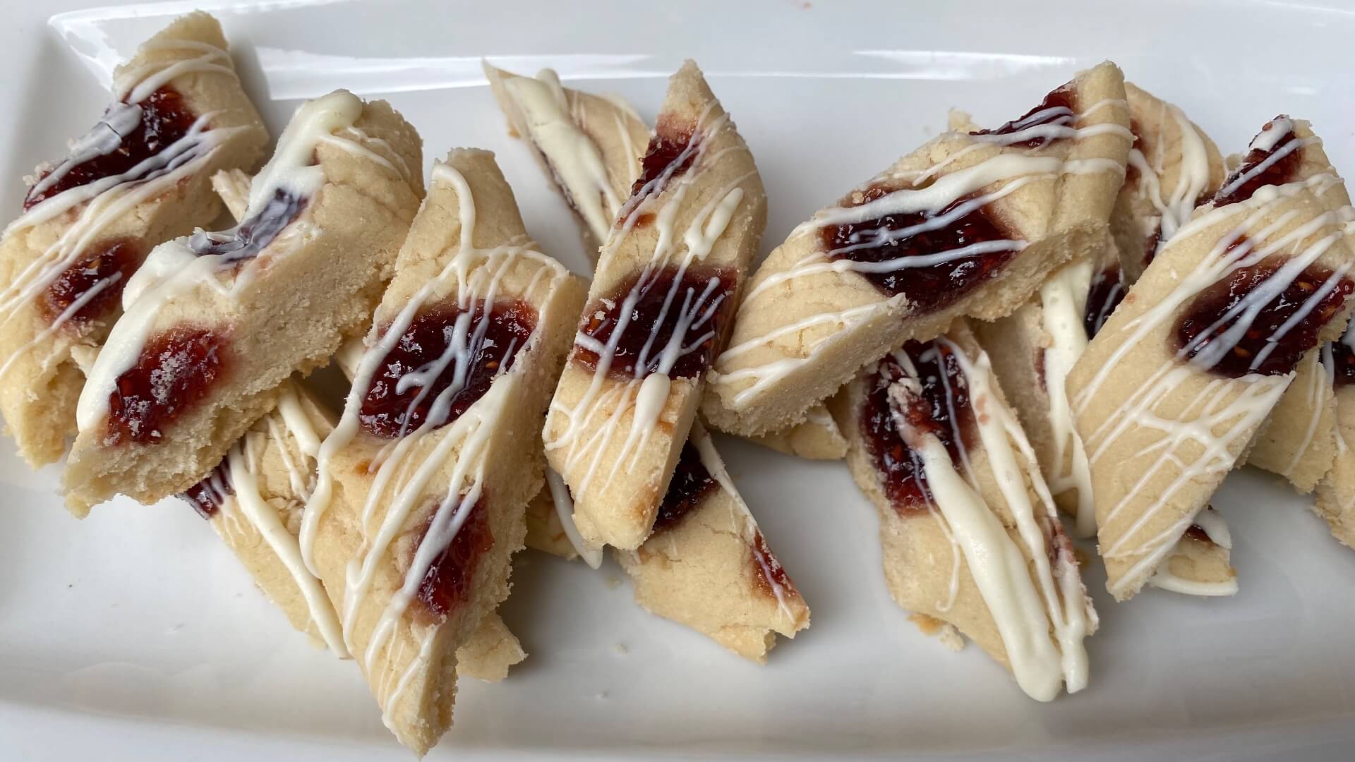 slices of shortbread cookies with ribbons of raspberry jam and drizzled with a white icing.